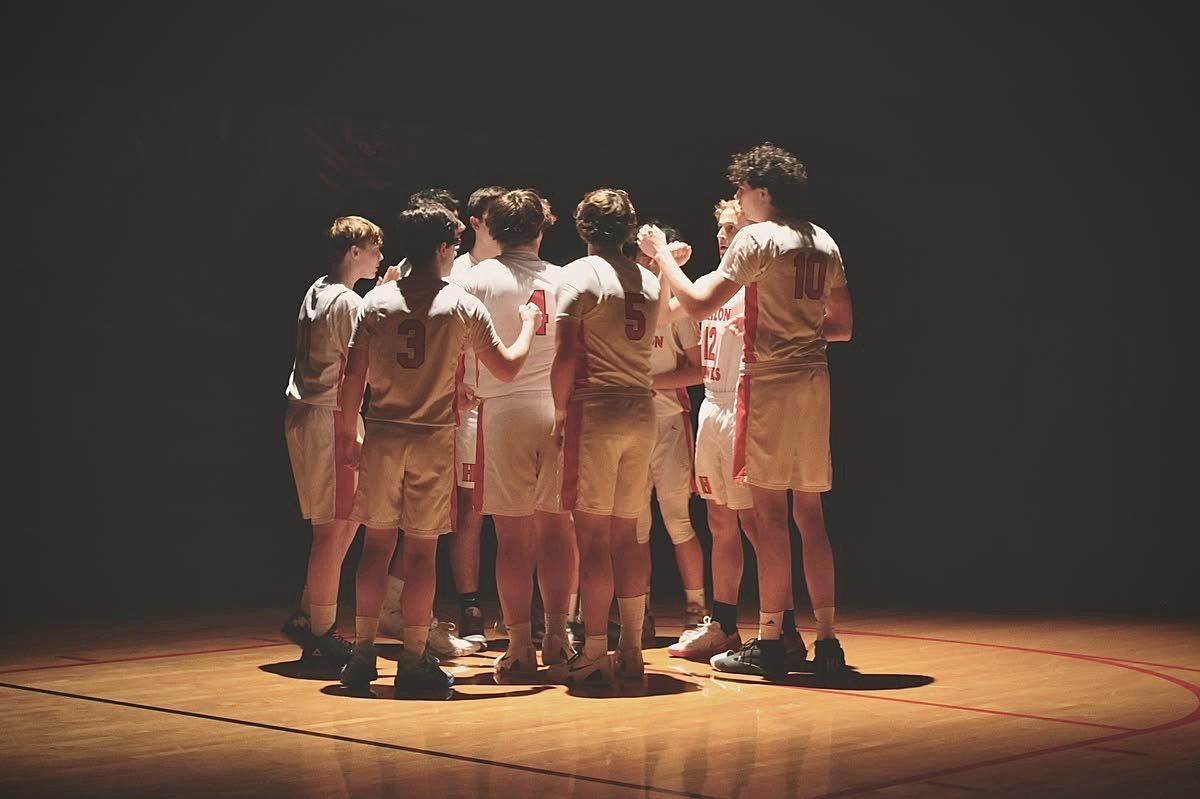 A youth team huddles together under the lights before the game