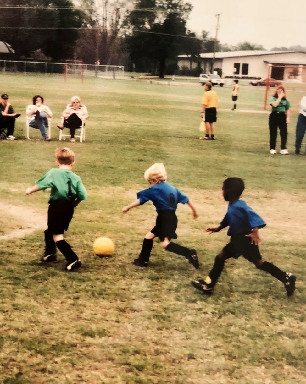 Young kids chasing a soccer ball at a rec game